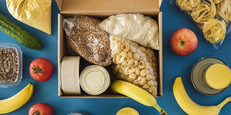 pantry staples within a carboard box placed on a blue, hard surface